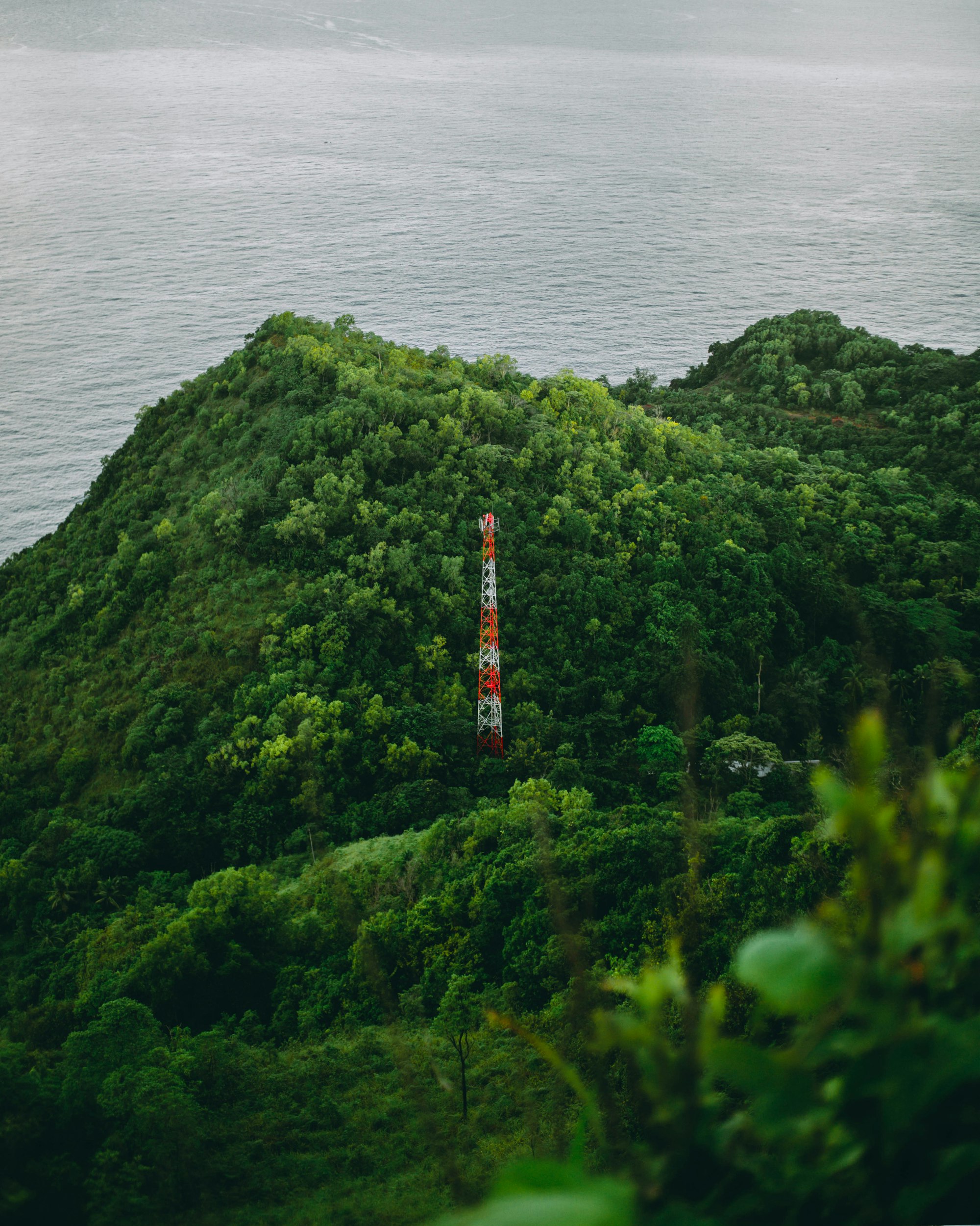 red and white tower on top of green mountain